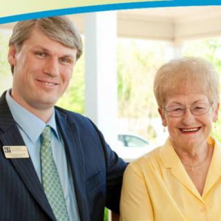 A man and an elderly woman are smiling indoors.