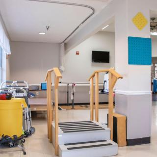 A physical therapy room featuring equipment used for rehabilitation exercises, including a set of practice stairs.