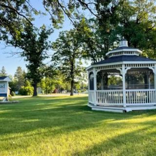 A picturesque gazebo in a peaceful park setting surrounded by lush greenery.