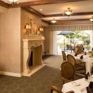 An elegant dining room with a fireplace and chandelier, offering a view of the outdoor patio.