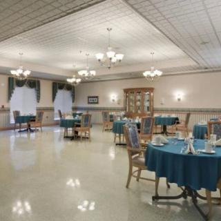 An elegantly set dining area with multiple tables and chandeliers in a spacious interior.