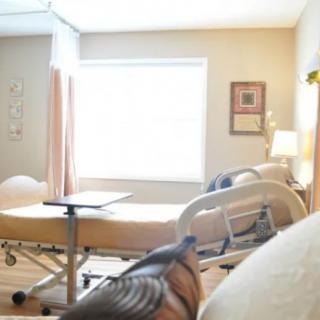A clean and well-lit hospital room with a bed and a window.