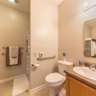 A modern and clean bathroom featuring a toilet, sink, mirror, and neatly arranged towels.