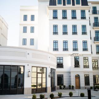 A modern, multi-story building with a white facade and numerous windows.