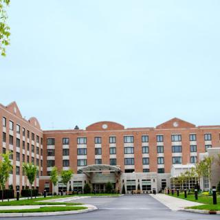 A large brick hotel building with a central entrance and surrounding landscaping.
