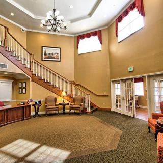 A spacious lobby with a grand staircase, elegant chandelier, and comfortable seating.