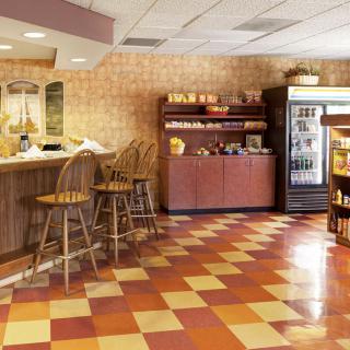 A cozy cafe interior with a counter and seating area, featuring tile flooring and a selection of snacks and beverages.