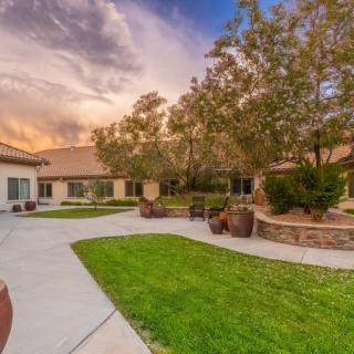 A serene courtyard at sunset with well-maintained lawns and trees surrounding a building.