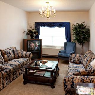 A cozy living room with patterned sofas, a coffee table, and a television.