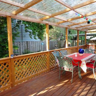 A cozy outdoor deck with a wooden pergola and dining area.