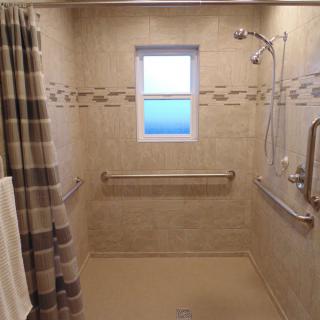 A fully accessible walk-in shower with tiled walls and grab bars for safety.