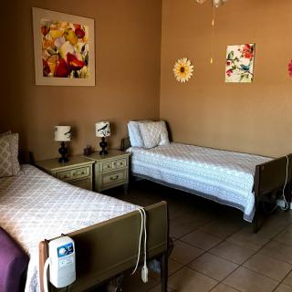 A cozy bedroom with two single beds, decorated with floral wall art and bedside lamps.