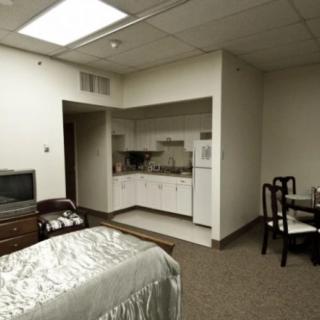 A compact studio apartment featuring a bed, kitchenette, and small dining area.