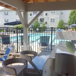A view of a swimming pool area with seating and umbrellas at an apartment complex.