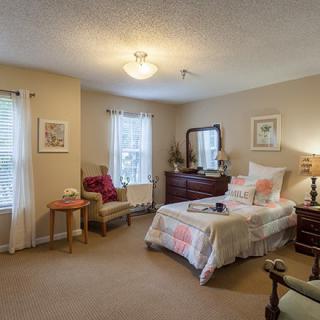 A cozy bedroom with a single bed, dresser, and decorative furnishings.
