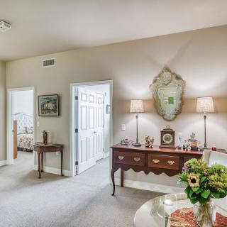 A cozy bedroom with elegant furniture and decor, highlighted by a decorative mirror and fresh flowers.