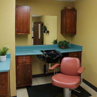 A cozy hair salon station featuring a styling chair, sink, and storage cabinets.