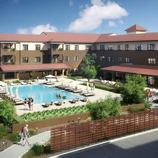 A beautiful hotel featuring a spacious outdoor swimming pool and lush landscaping.