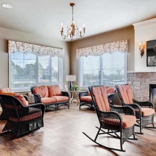 A spacious living room with ample seating, featuring rocking chairs and a cozy fireplace.