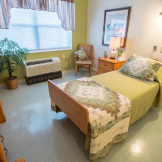 A cozy bedroom with a single bed, featuring warm lighting and decorative elements.