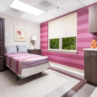 A modern bedroom with pink striped walls and a single bed.
