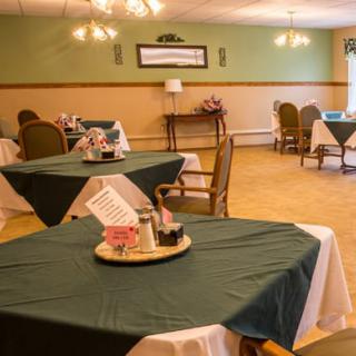 A warmly lit dining room with neatly arranged tables and decorative centerpieces.