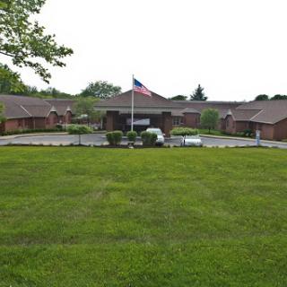 A view of a building with a flag in the foreground, surrounded by well-maintained grass.
