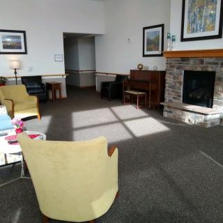 A cozy living room with chairs, a fireplace, and a piano.