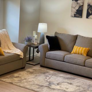 A cozy living room with stylish grey sofas and yellow pillows, featuring a lamp and decorative elements.