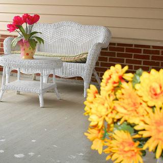 A cozy porch with wicker furniture and vibrant flowers.