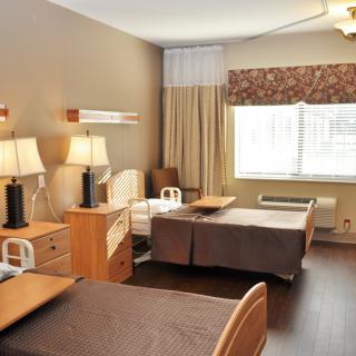A shared hospital room with two beds and basic furnishings.