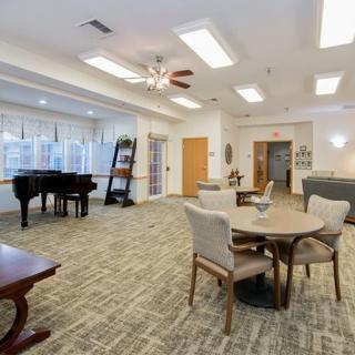 A welcoming room with a piano, tables, and chairs arranged for relaxation and socializing.