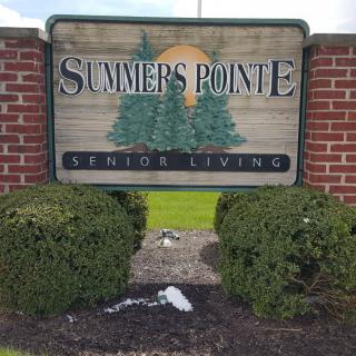 Sign for Summers Pointe Senior Living surrounded by bushes and brickwork.