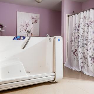 A modern bathroom featuring a walk-in tub with pink walls and a floral shower curtain.