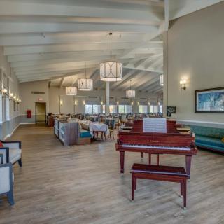 A spacious lounge area featuring a piano, comfortable seating, and elegant lighting.