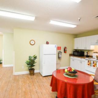 A modern kitchen and dining area with a refrigerator, table, and wooden flooring.