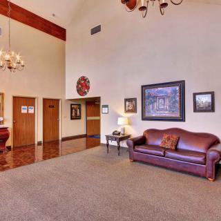 A spacious lobby featuring a leather sofa, chandeliers, and decorative artwork on the walls.