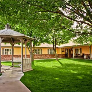 A peaceful courtyard with a gazebo, surrounded by a well-maintained lawn and trees.