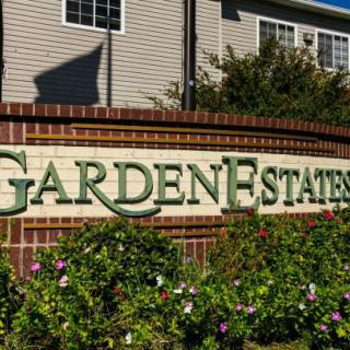 Entrance sign for Garden Estates surrounded by flowers.