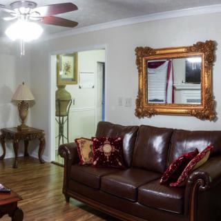 A cozy living room featuring a leather sofa, ornate mirror, and warm lighting.