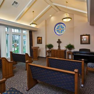 A peaceful chapel interior with wooden pews and a stained glass window.