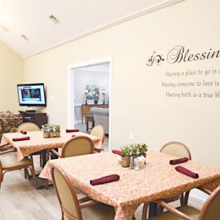 A cozy dining area with neatly arranged tables and chairs, decorated with plants and wall art.