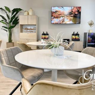 A modern interior with a round dining table and chairs, featuring plants and a TV for a cozy setting.
