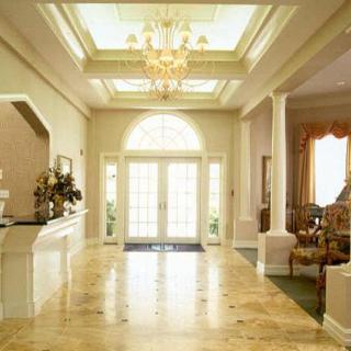 A luxurious lobby with a marble floor and chandelier, featuring natural light streaming through large windows.