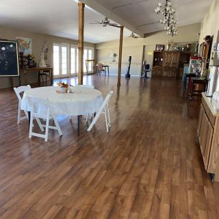 A spacious event hall with wood flooring, decorated with tables and chairs.