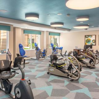 A modern gym with various exercise equipment including stationary bikes and cardio machines.