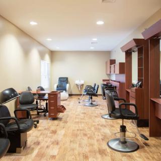 An empty hair salon with chairs and mirrors lined up along the walls.