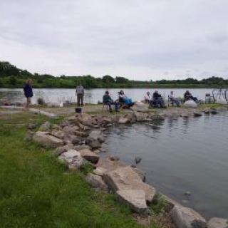 A group of people enjoying a fishing day at the lake on a cloudy afternoon.