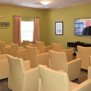 A small theater room with rows of chairs facing a television screen.
