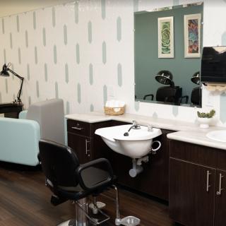 Modern hair salon interior with a styling chair, sink, and mirror.